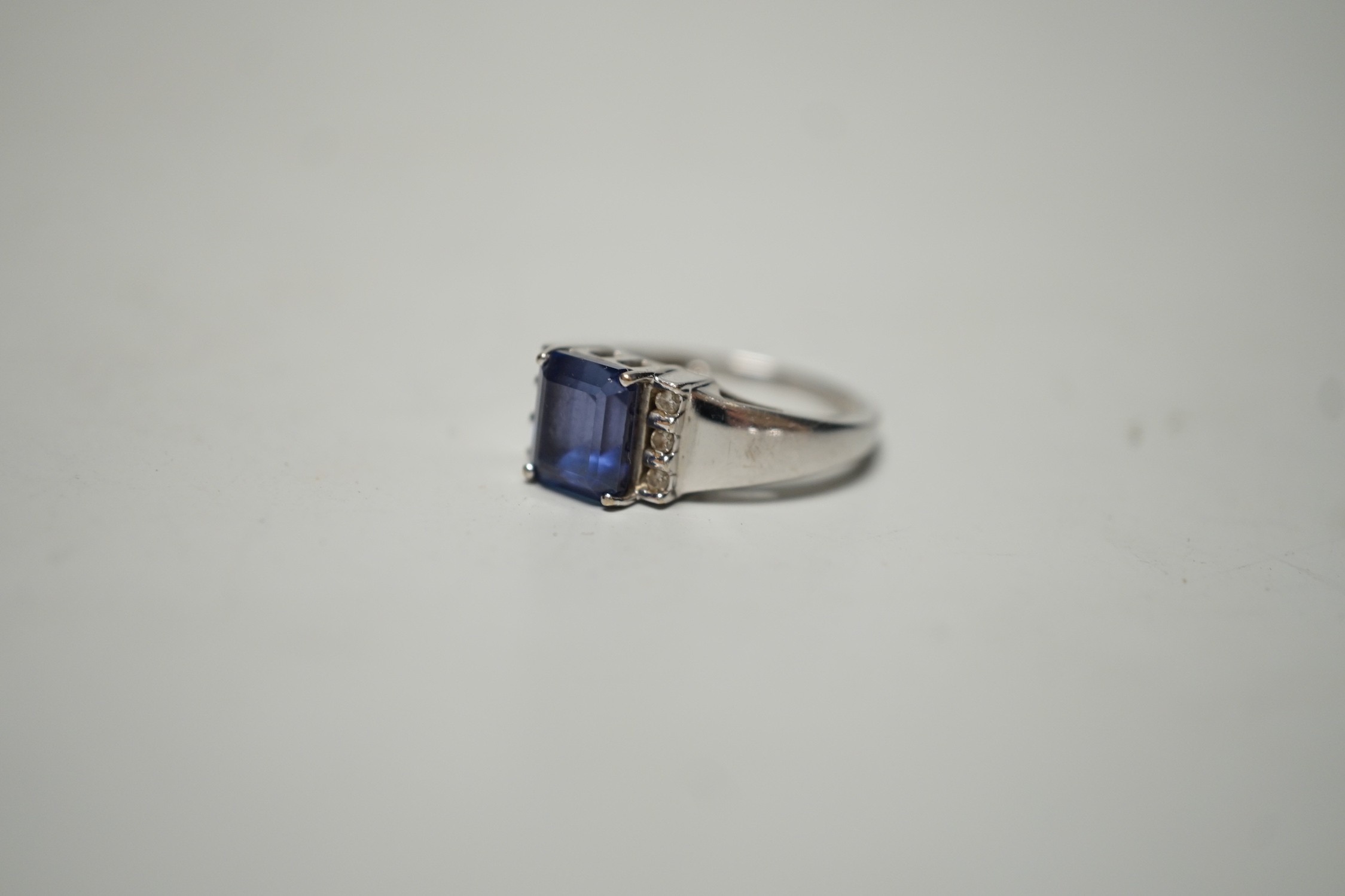 A modern 18k, single stone emerald cut tanzanite and six stone diamond cluster set ring, size O, gross weight 5 grams, with accompanying IGI report dated 6/9/2006.